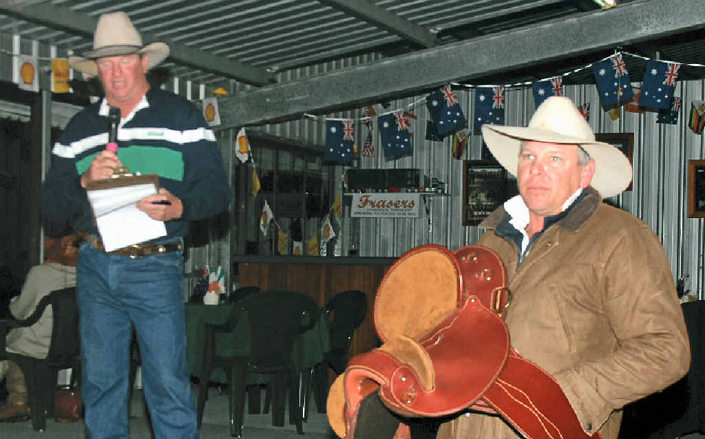 President of the Tansey Polocrosse Club and auctioneer Justin Hafey and Alex Rowe’s husband Terrrence Rowe with the saddle which was one of many items up for grabs at the auction.